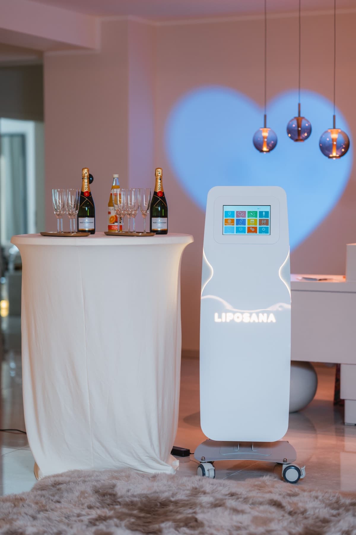 Stehtisch mit Champagner und Gläsern bei einem LIPOSANA3® Abend, im Hintergrund ein Herz aus Licht