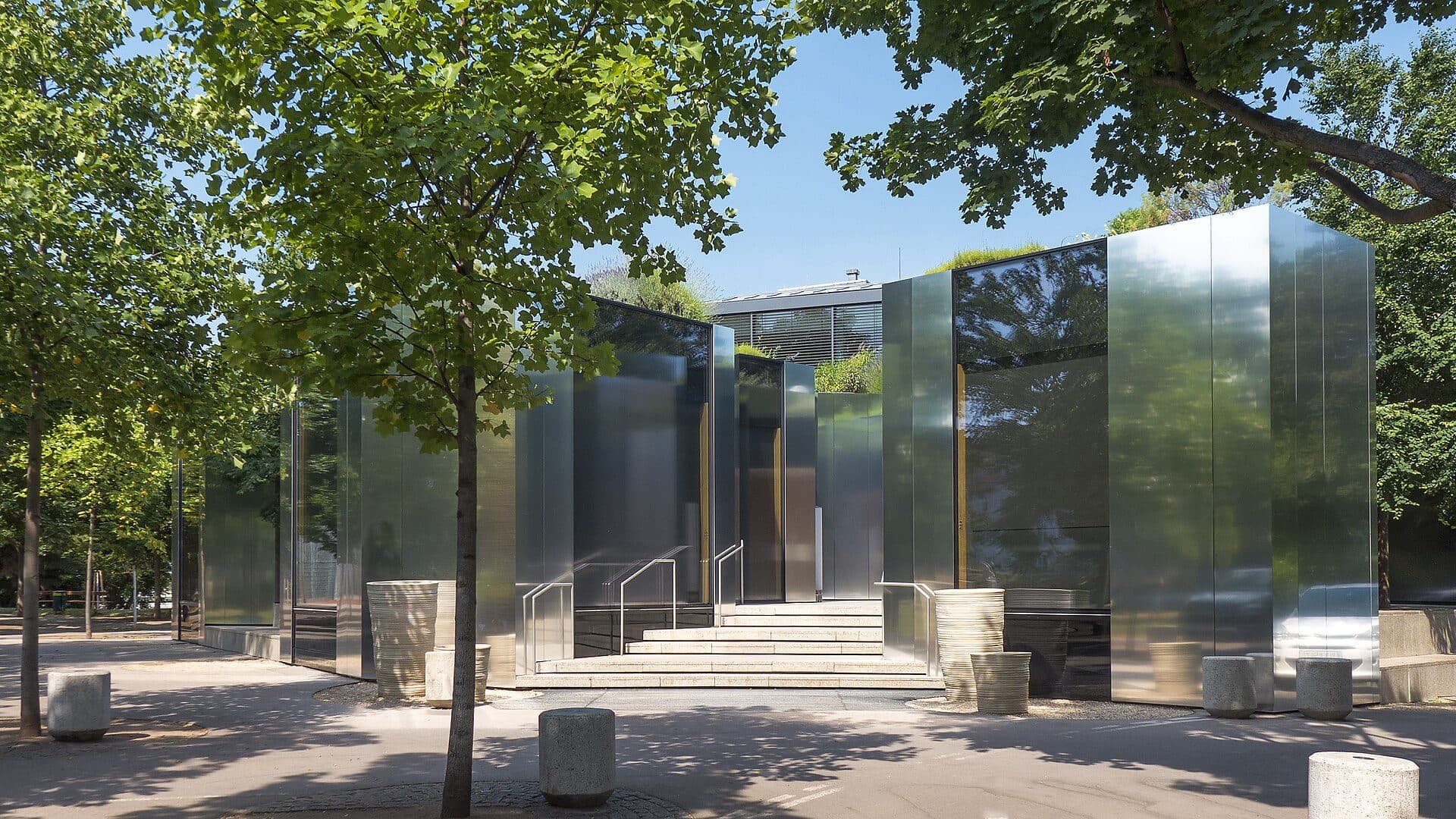 Eingang des Steirereck mit verspiegelter Fassade zwischen Bäumen im Stadtpark